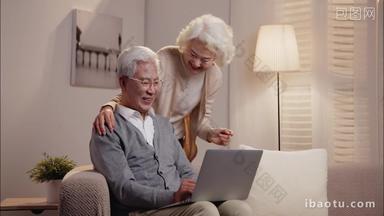 老年夫妇<strong>坐</strong>在<strong>沙发上</strong>使用笔记本电脑